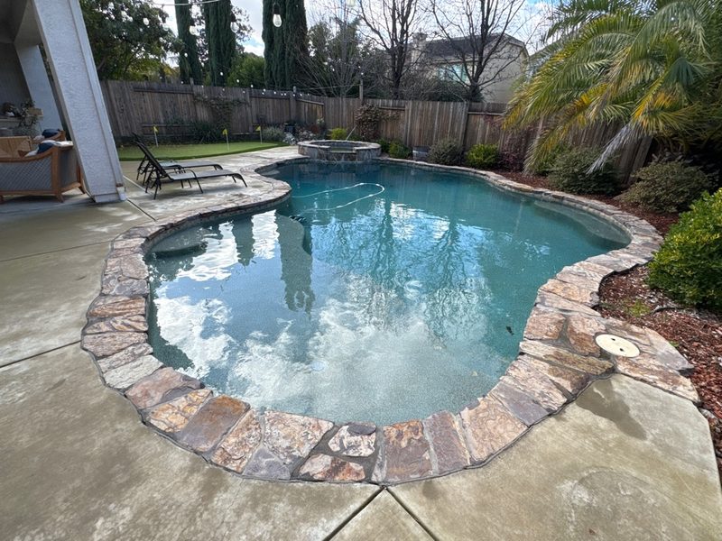 Freeform pool with natural stone coping and string lights in West Roseville 95747