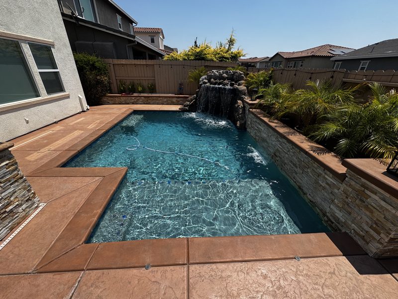 Crystal clear pool with rock waterfall feature serviced by Private Oasis Pools in Roseville CA
